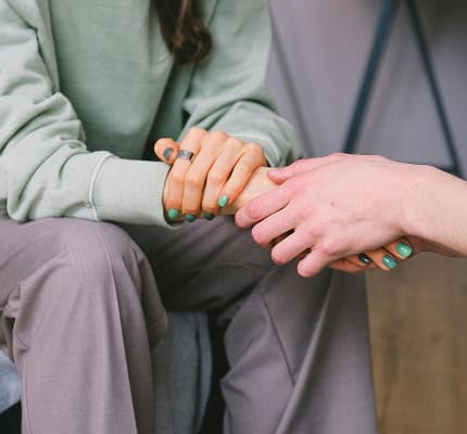 A person comforting another by holding their hand